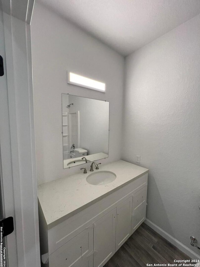 bathroom featuring walk in shower, vanity, baseboards, and wood finished floors