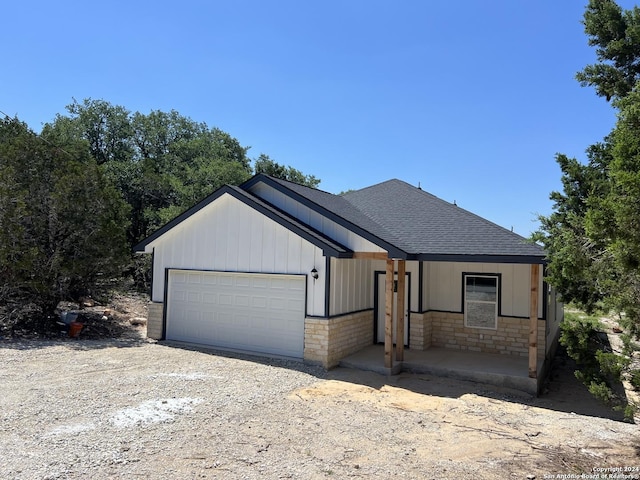 view of front of house with a garage, stone siding, driveway, and a shingled roof