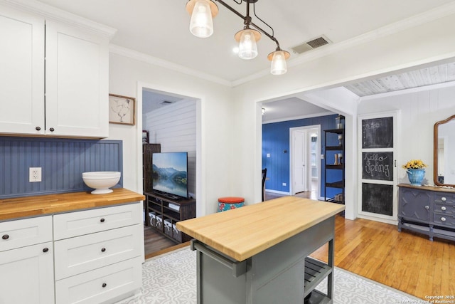 kitchen featuring visible vents, ornamental molding, wood counters, light wood-style floors, and white cabinets