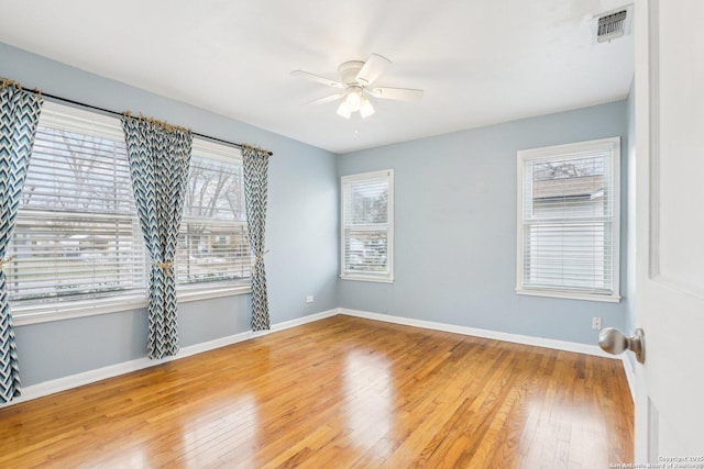 unfurnished room with visible vents, baseboards, hardwood / wood-style floors, and a ceiling fan