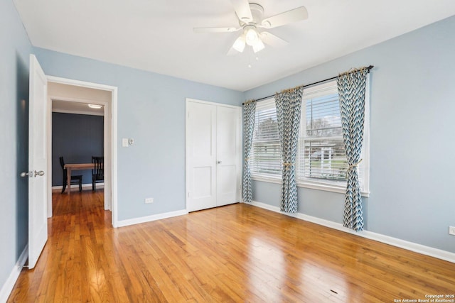 unfurnished bedroom featuring light wood finished floors, a closet, baseboards, and a ceiling fan