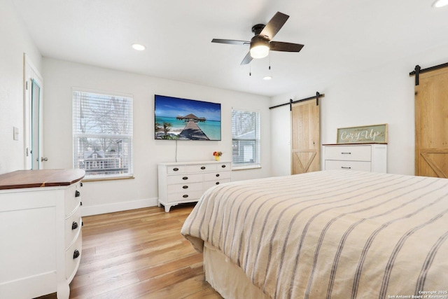 bedroom with recessed lighting, a barn door, light wood finished floors, baseboards, and ceiling fan