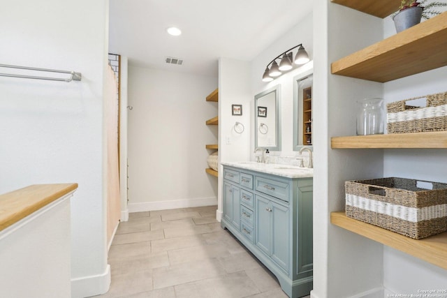 full bathroom featuring a sink, visible vents, baseboards, and double vanity