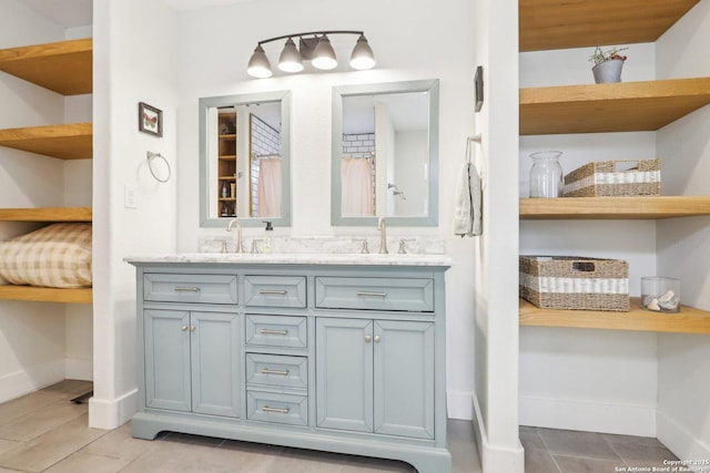 full bathroom featuring double vanity, baseboards, and a sink