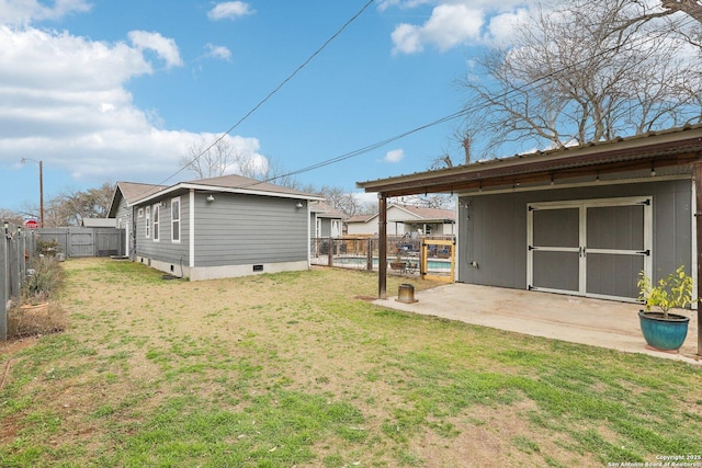 back of house with a patio, an outbuilding, a fenced backyard, crawl space, and a lawn