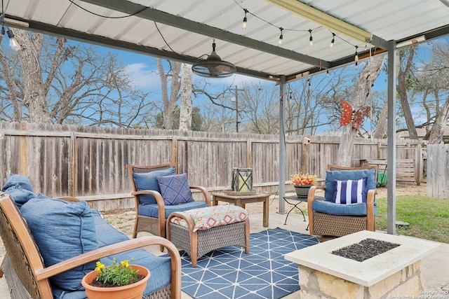 view of patio with an outdoor living space with a fire pit, a fenced backyard, and a ceiling fan