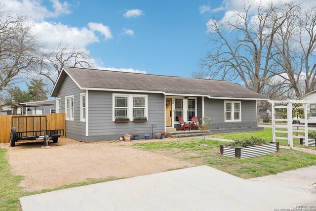 view of front of property featuring roof with shingles, covered porch, a front lawn, and fence