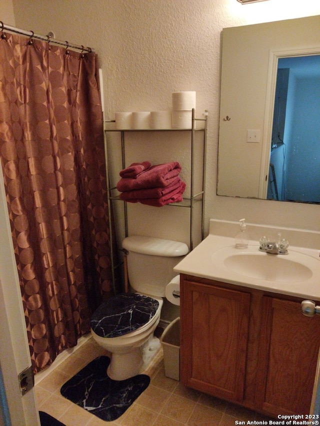 full bathroom with toilet, curtained shower, vanity, and a textured wall