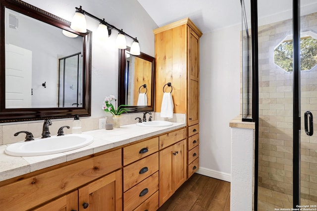 full bathroom featuring double vanity, a stall shower, wood finished floors, and a sink