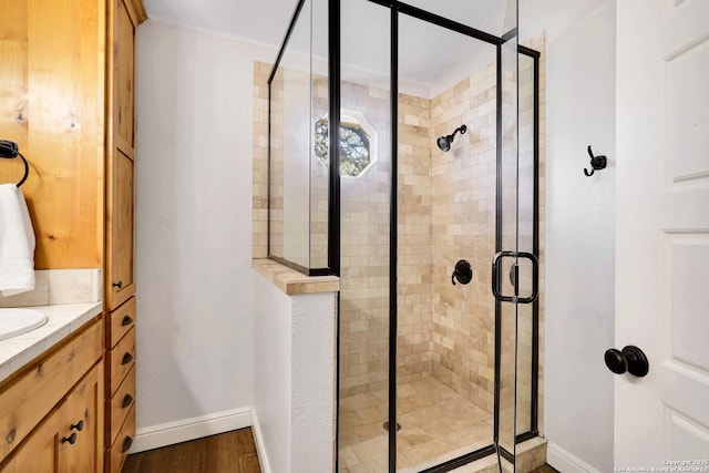 bathroom featuring a stall shower, vanity, and baseboards