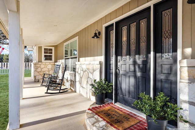 view of exterior entry featuring stone siding and covered porch