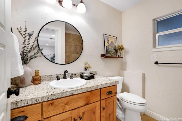 bathroom featuring toilet, vanity, and a textured wall