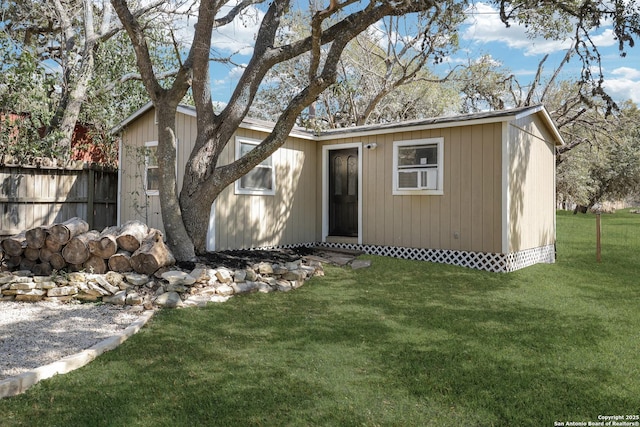 view of front of house with an outdoor structure, a front yard, and fence