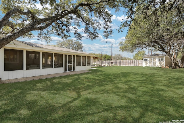 view of yard with a sunroom, an outdoor structure, and fence