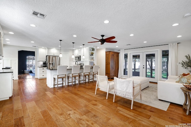 living area featuring recessed lighting, light wood-style floors, visible vents, and french doors