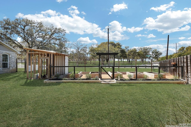 view of yard with an outbuilding, fence, and a garden