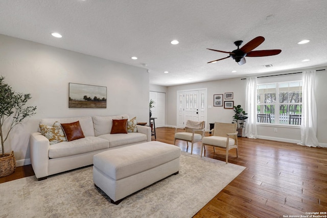 living area with visible vents, recessed lighting, a textured ceiling, and wood finished floors