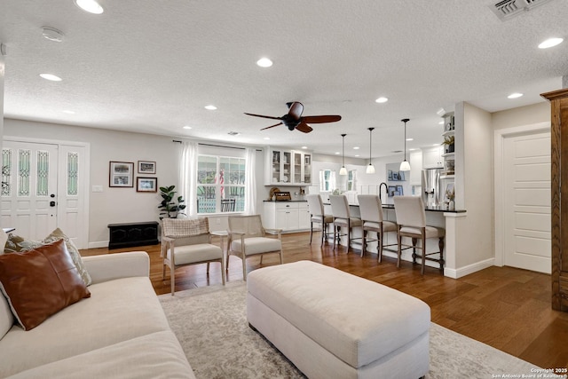 living room featuring visible vents, recessed lighting, a textured ceiling, and wood finished floors