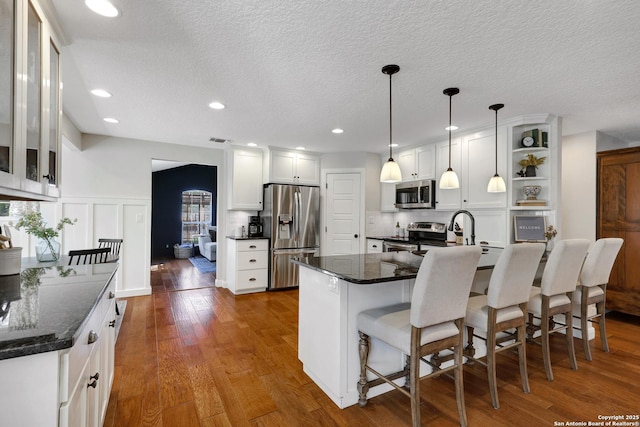 kitchen with open shelves, a breakfast bar, white cabinets, stainless steel appliances, and wood-type flooring