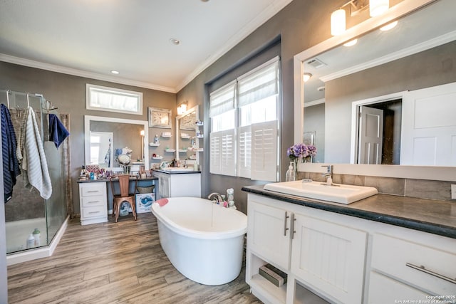 bathroom with vanity, wood finished floors, a freestanding tub, ornamental molding, and a shower stall