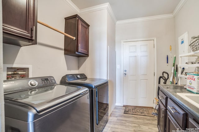 clothes washing area with cabinet space, ornamental molding, light wood-style floors, and separate washer and dryer