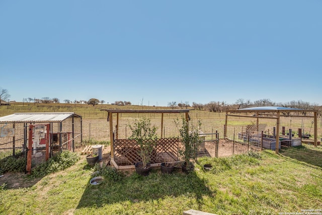 view of yard with an outdoor structure, a garden, and a rural view