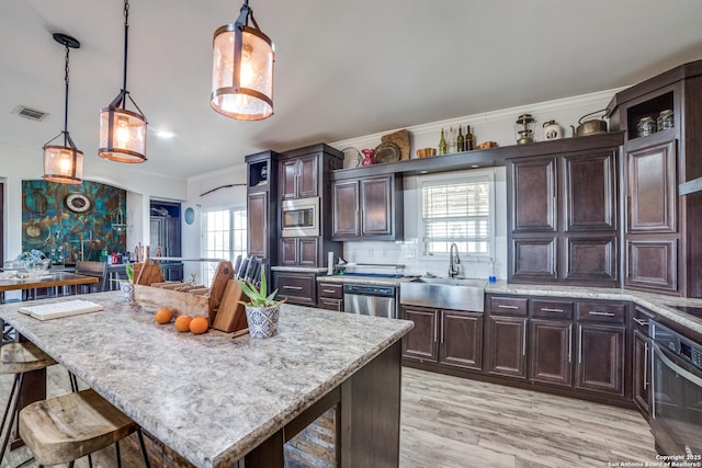 kitchen featuring visible vents, a sink, stainless steel appliances, crown molding, and tasteful backsplash