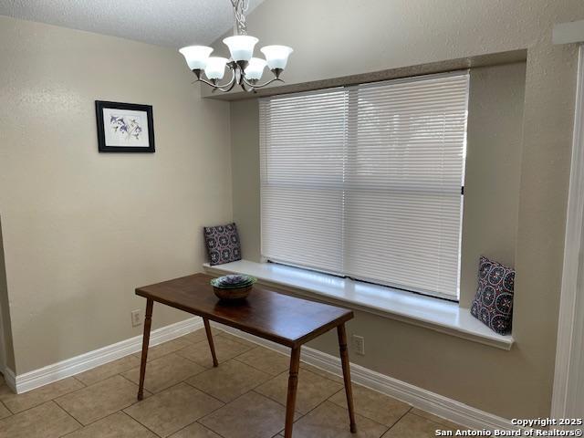 unfurnished dining area with light tile patterned floors, baseboards, and an inviting chandelier