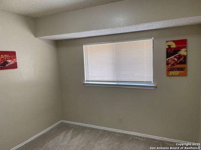 spare room featuring baseboards, a textured ceiling, and carpet