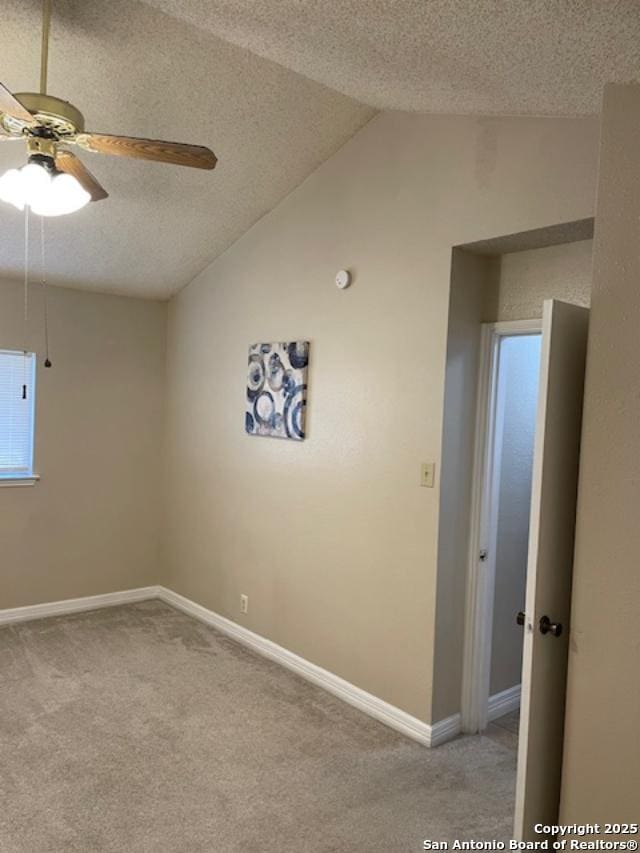 unfurnished room featuring a textured ceiling, baseboards, light colored carpet, and vaulted ceiling