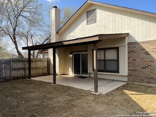 rear view of property with a patio area, brick siding, a chimney, and fence