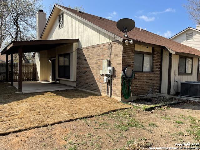 rear view of property featuring brick siding, fence, cooling unit, a chimney, and a patio