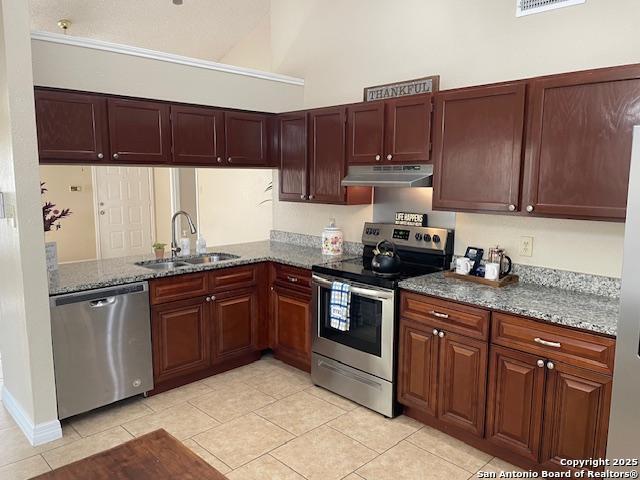 kitchen with under cabinet range hood, stone countertops, stainless steel appliances, and a sink