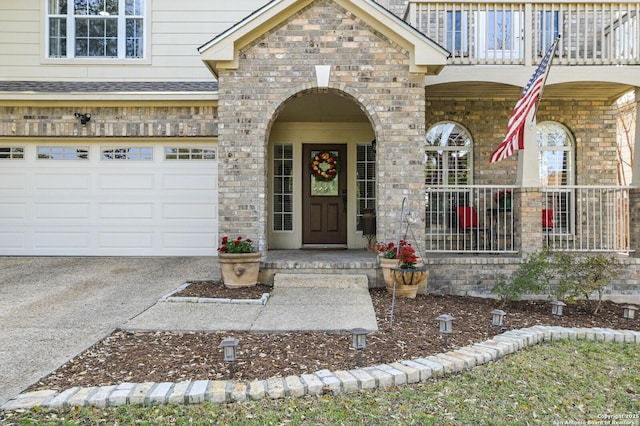 entrance to property with covered porch, driveway, a shingled roof, and an attached garage