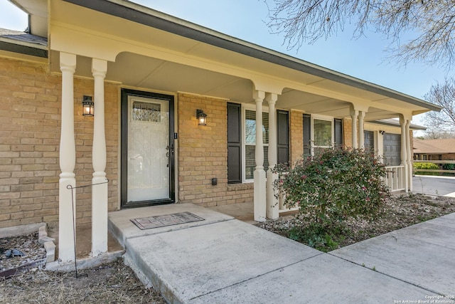 view of exterior entry featuring brick siding and covered porch