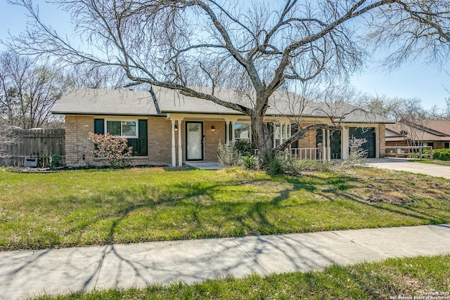 ranch-style home featuring driveway, a front lawn, fence, an attached garage, and brick siding