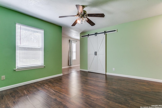 5918 Oak Country Way, San Antonio, TX 78247 - unfurnished bedroom with baseboards, a textured ceiling, a barn door, a ceiling fan, and wood finished floors