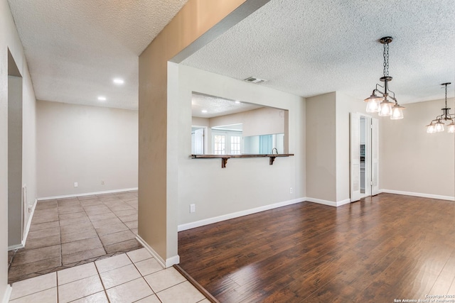 empty room featuring visible vents, wood finished floors, baseboards, and a textured ceiling