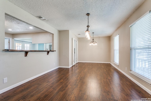 5918 Oak Country Way, San Antonio, TX 78247 - spare room with a textured ceiling, dark wood-style floors, baseboards, visible vents, and an inviting chandelier