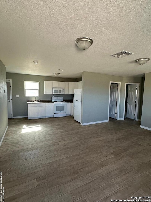 kitchen featuring visible vents, a sink, dark wood-style floors, white cabinetry, and white appliances