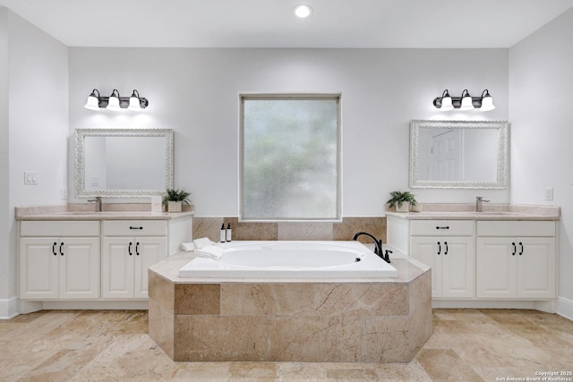 bathroom featuring a sink, a garden tub, and two vanities