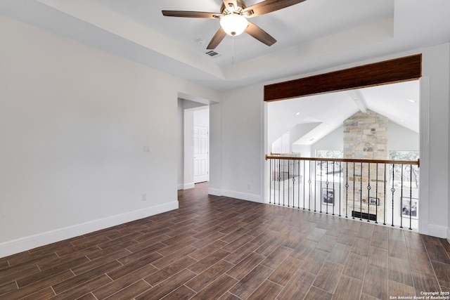 spare room with ceiling fan, baseboards, wood tiled floor, lofted ceiling with beams, and a tray ceiling