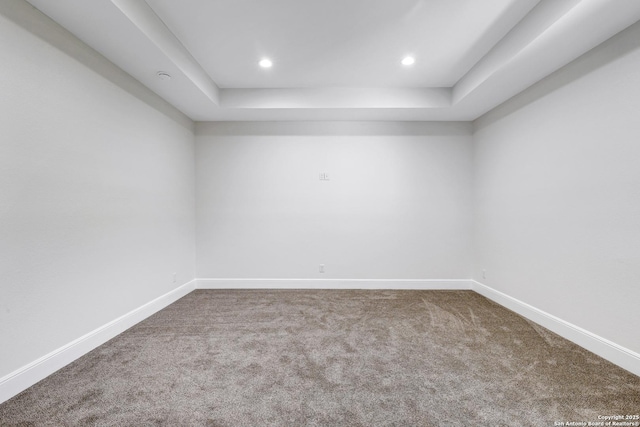 spare room featuring a raised ceiling, recessed lighting, carpet, and baseboards