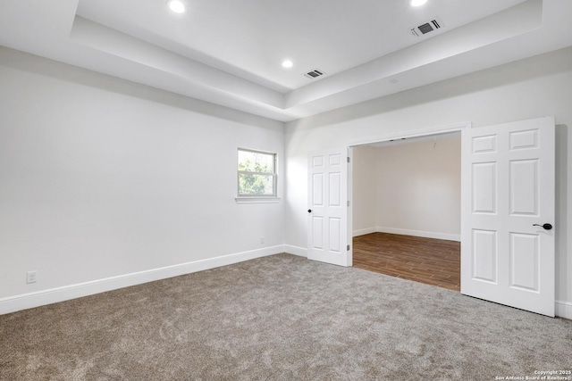 unfurnished bedroom with visible vents, baseboards, a raised ceiling, and carpet