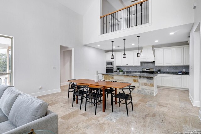 dining space with recessed lighting, baseboards, and a towering ceiling