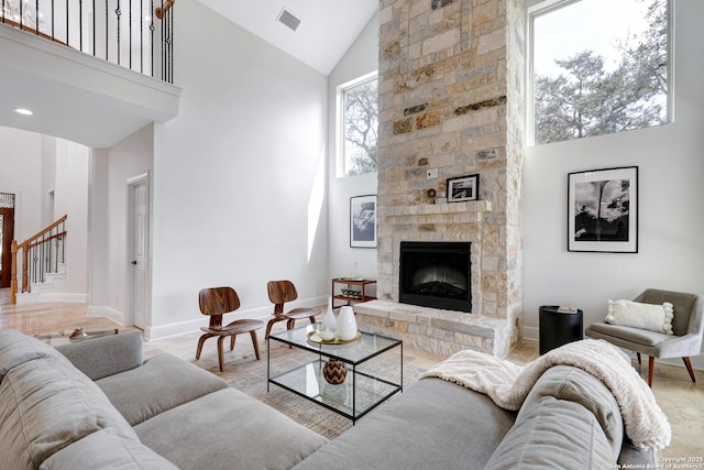 living room with visible vents, baseboards, stairs, a fireplace, and high vaulted ceiling