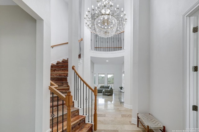 foyer entrance with stairs, a high ceiling, baseboards, and a chandelier