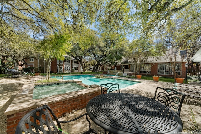 pool with a patio area, outdoor dining space, and an in ground hot tub