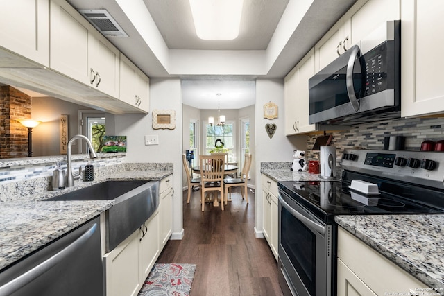 kitchen featuring visible vents, dark wood-style flooring, a sink, decorative backsplash, and stainless steel appliances