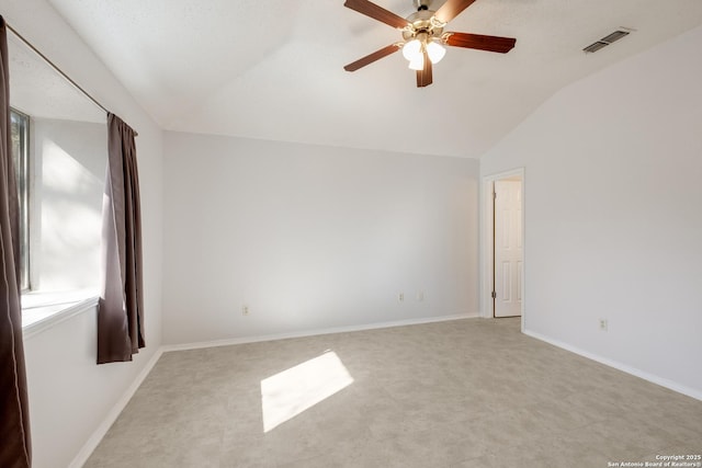 spare room featuring visible vents, lofted ceiling, baseboards, and a ceiling fan